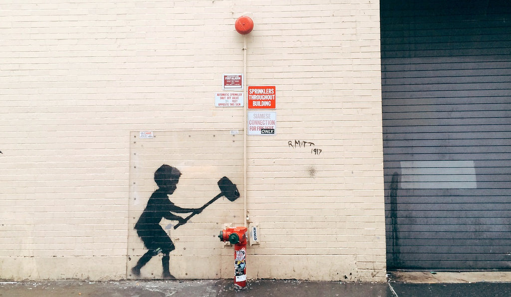 Street wall art in Europe of boy hammering fire hydrant 