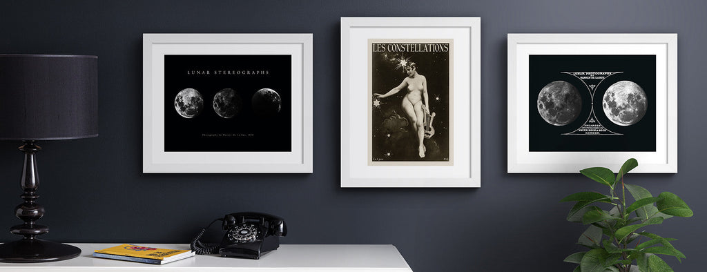Space and constellation wall art prints hung up on a dark blue wall.