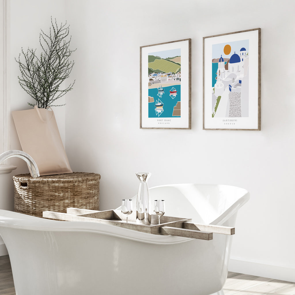 Two wall art prints of seaside travel destinations, hung up on a bathroom wall.
