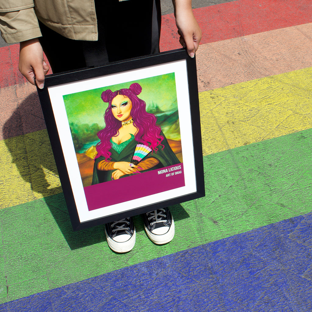 Reimagined classical art print featuring a Drag Queen posing as 'Mona Lisa'. Art print is in a black frame being held over a rainbow walkway.