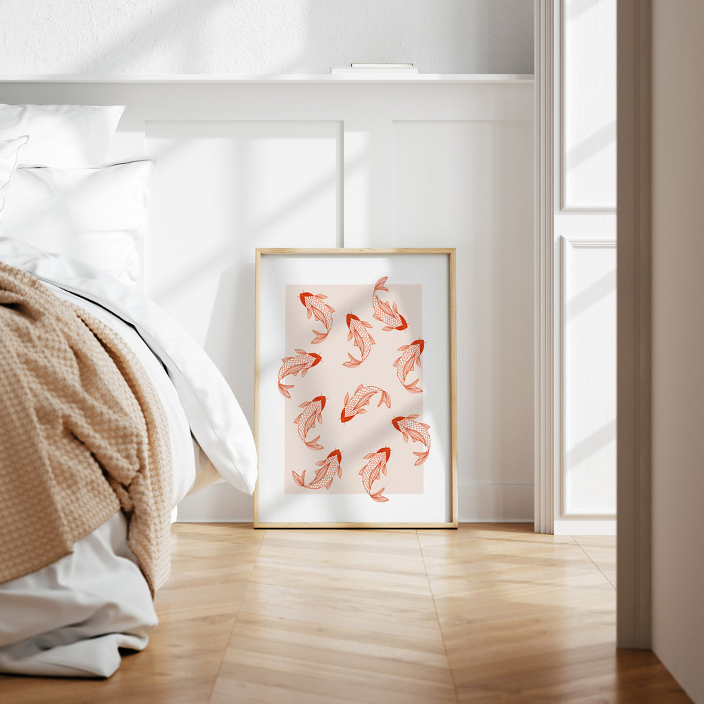 Pastel art print featuring a patterned illustration of pink koi, on a pale pink background. Art print is framed and leaning against a wall in a bedroom.