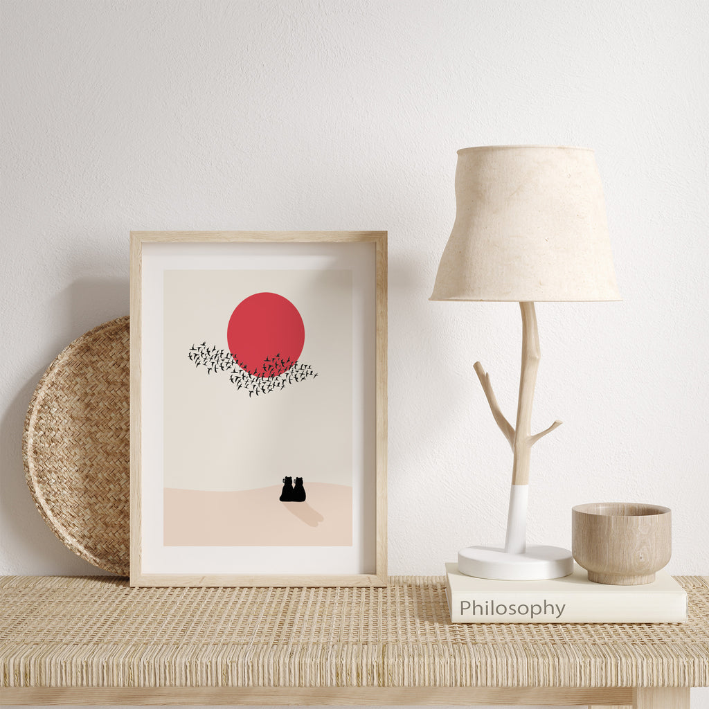 Two bears watching a red sunset together, with a flock of birds going past. Art print is leaning against a white wall.