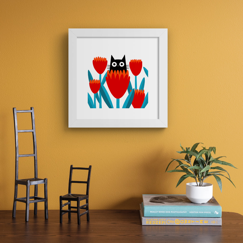 Wall art print of a playful cat in flowers, hung up on an orange wall.