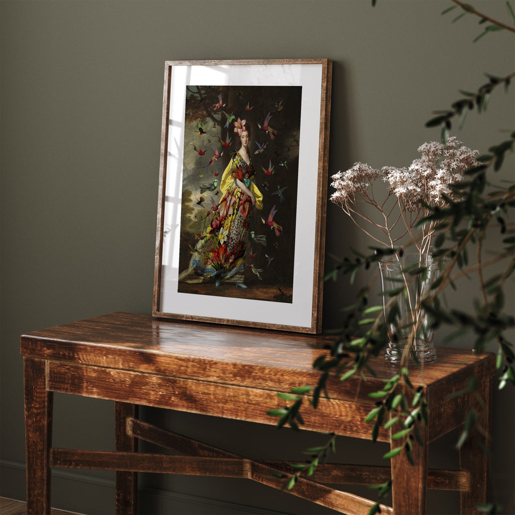 Vibrant art print featuring birds flocking around a woman dressed in bright yellow floral packaging. Art print is settled on a table, leaning against a green wall.