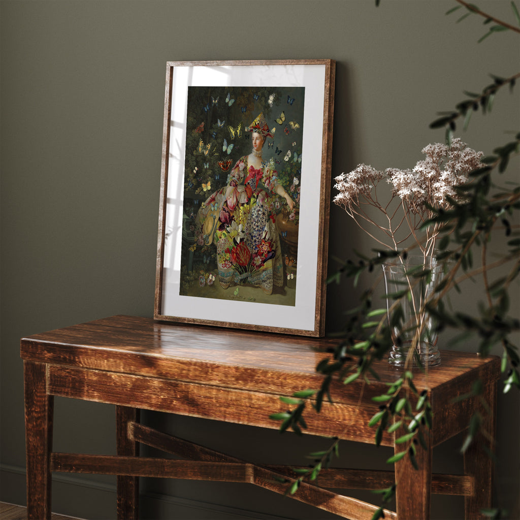Vibrant art print of butterflies flitting around a classical picture of a woman posing in an eccentric dress. Art print is leaning against a green wall on a dresser.