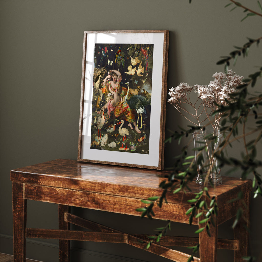 Stunning 'Pop-Surrealist' art print featuring botanicals and animals fluttering around a woman and a child. Art print is leaning on a wooden dresser against a dark green wall.