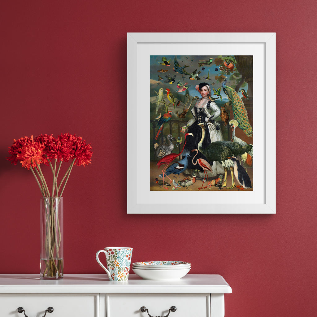 Stunning 'Pop-Surrealist' art print featuring a vast array of different birds flocking around an elegant woman. Art print is hung up on a red wall.