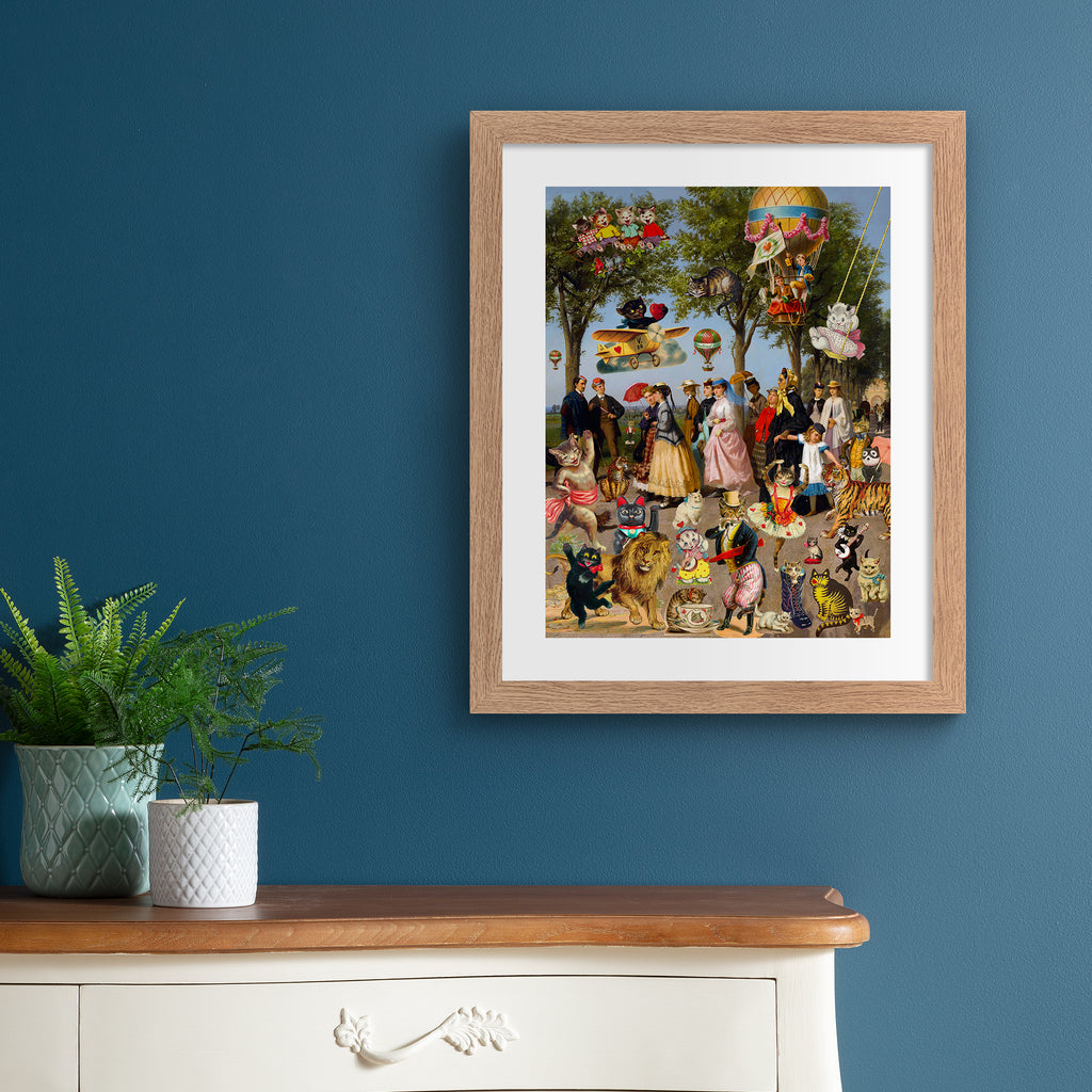 Stunning 'Pop-Surrealist' art print featuring a picnic spread of cats, people and playful characters on a bright summer day. Art print is hung up on a blue wall.