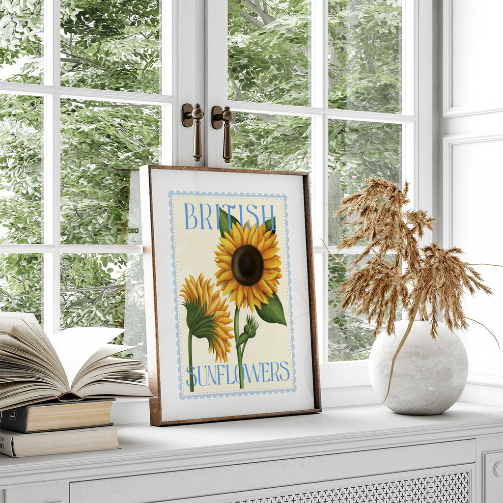 Sunflower art print featuring summery flowers and the text 'British Sunflowers'. Art print is leaning on a shelf against a window.