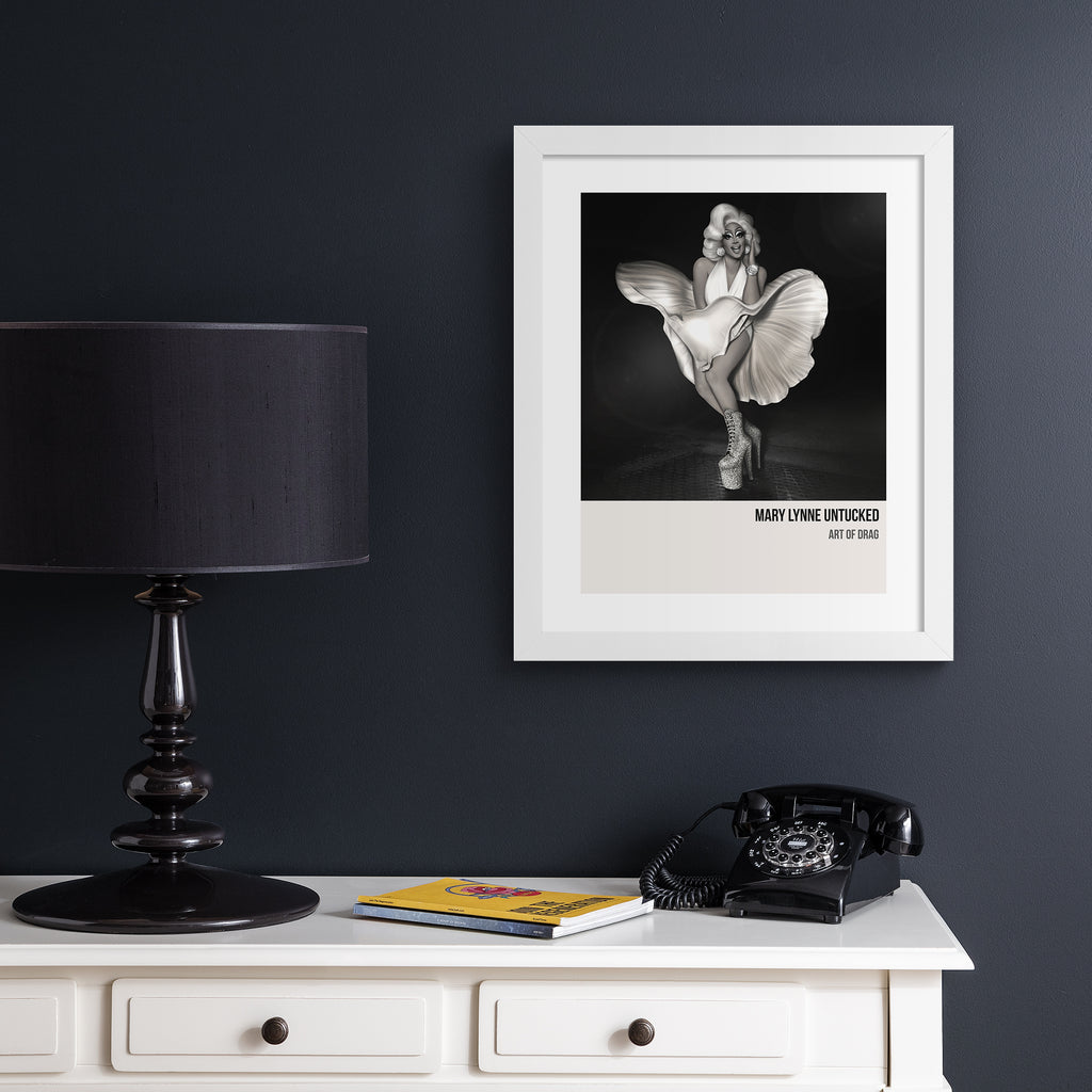 Reimagined classical art print featuring a Drag Queen recreating an iconic shot of Marilyn Monroe, hung up on a black wall.