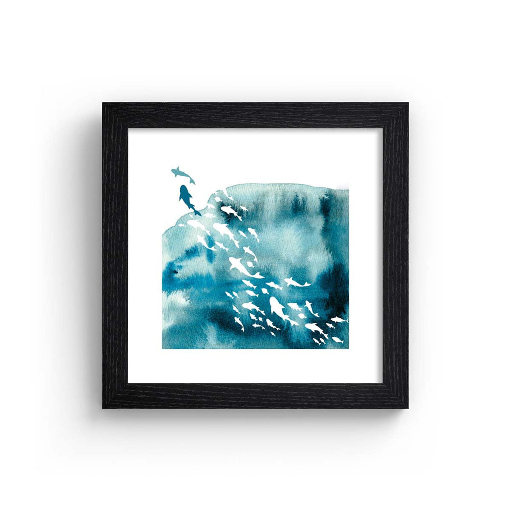 Vibrant watercolour art print featuring the silhouettes of fishes swimming in the ocean. Art print is in a black frame.