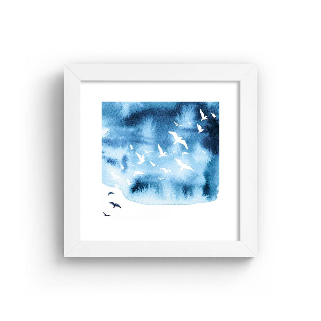 Watercolour art print featuring the silhouettes of birds flying against a brilliant blue sky. Art print is in a white frame.