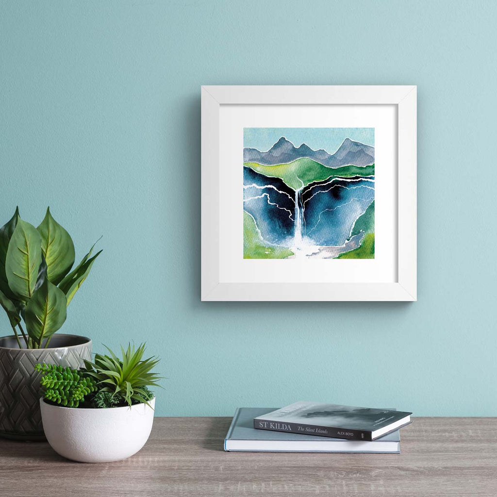 Beautiful watercolour art print featuring a waterfall flowing down a beautiful mountain landscape. Art print is hung up on a dark blue wall.
