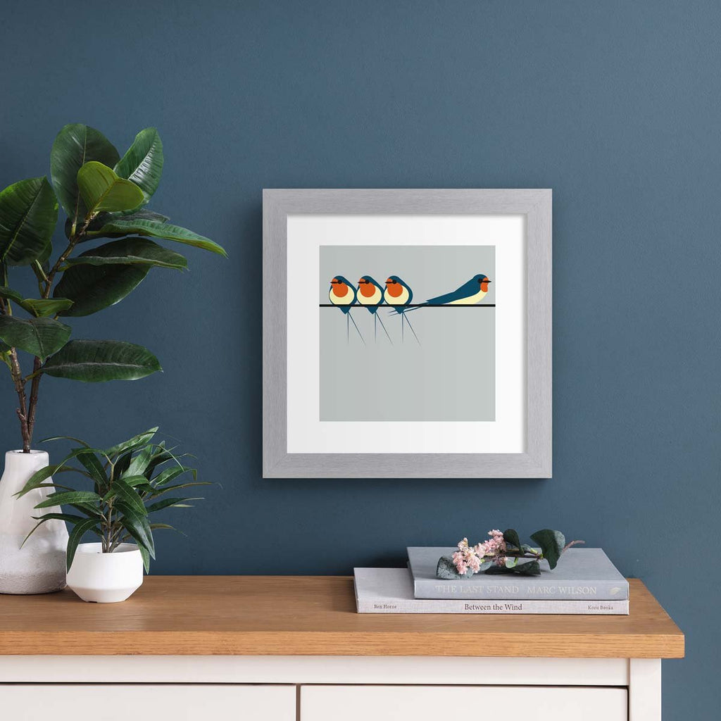 Minimalistic art print featuring three swallows perching on a line, in front of a blue background. Art print is hung up on a dark blue wall.