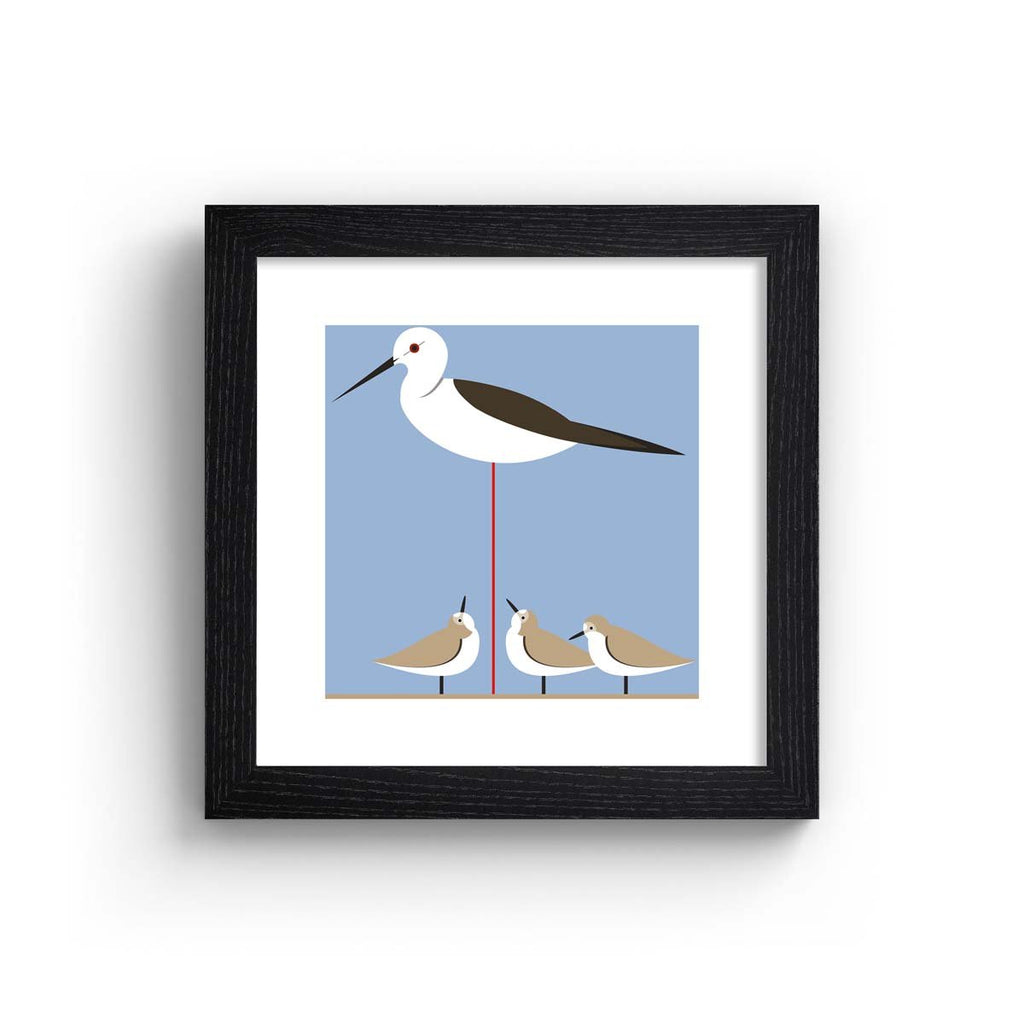 Minimalistic art print featuring small birds perched underneath a tall stilt. Art print is in a black frame.