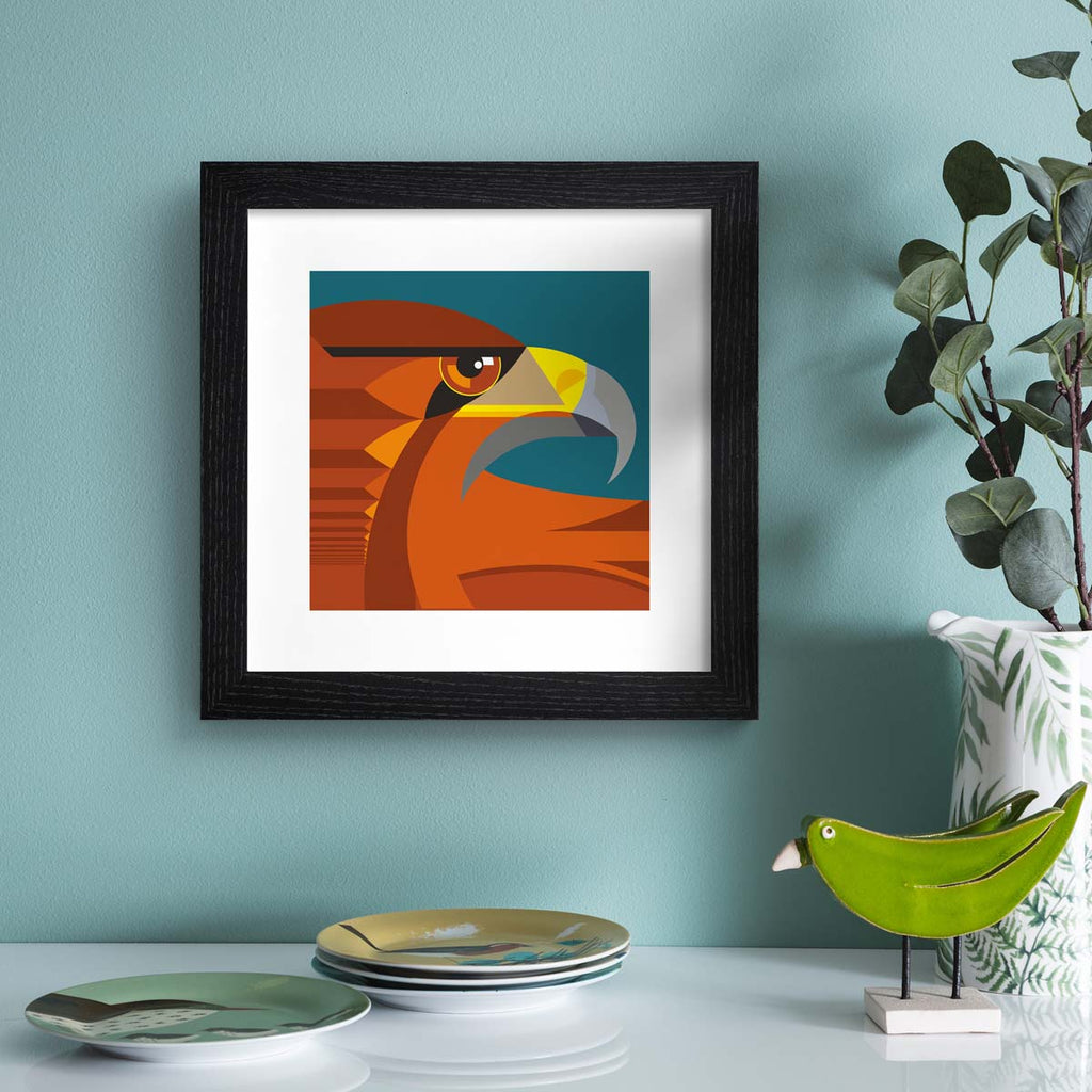 Minimalistic art print featuring a fierce golden eagle in front of a deep blue background. Art print is hung up on a bright blue wall.