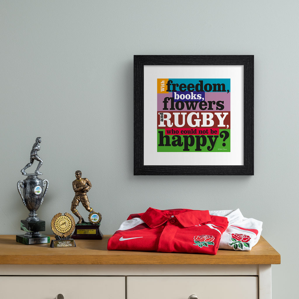 Art print featuring typography celebrating rugby, on a bright multicoloured background. Typography reads 'With Freedom, Books, Flowers And Rugby, Who Could Not By Happy'. Art print is hung up on a grey frame.