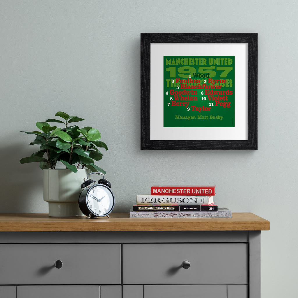 Sporty art print celebrating the Man United 1957 Team, on a bright green background, with red, black and green typography. Art print is hung up on a silver wall.