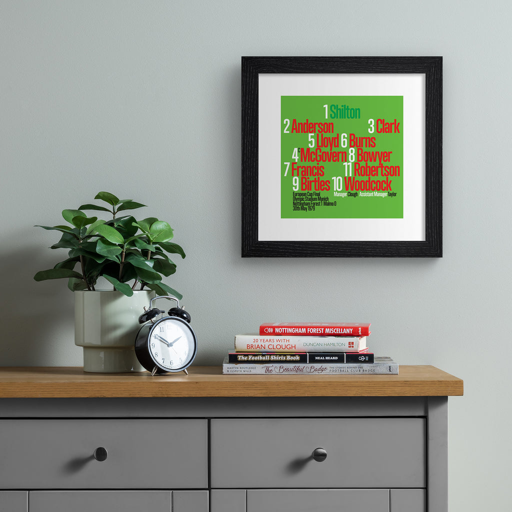Colourful art print celebrating the Nottingham Forest 1979 Team, on a bright green background, with red, black and green typography. Art print is hung up on a grey wall.