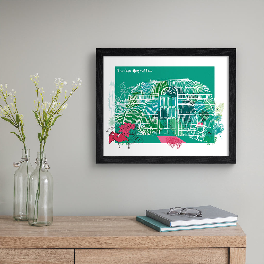 Vibrant travel art print featuring The Palm House At Kew Gardens in London, bordered by bright blooming flowers, on a green background. Title at the top left reads 'The Palm House At Kew'. Art print is hung up on a beige wall.