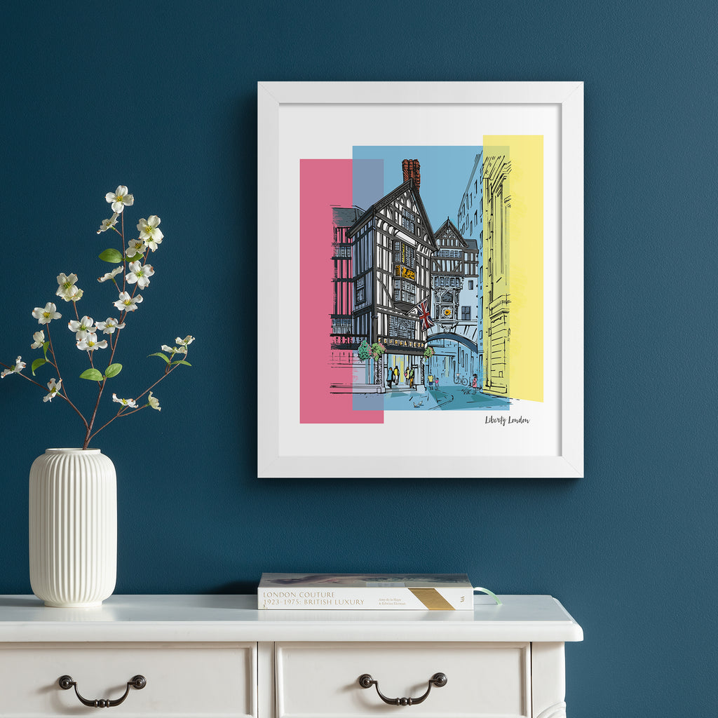 Vibrant travel art print featuring Liberty in London, amidst a brightly coloured background of pink, blue and yellow. Art print is hung up on a dark blue wall.
