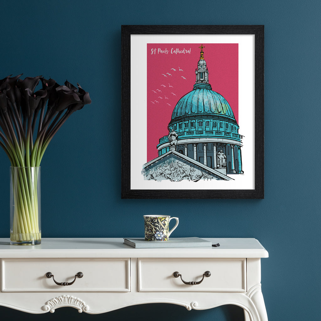 Vibrant travel art print featuring St Paul's Cathedral in London, amidst a bright pink background. Title in top left corner reads 'St Paul's Cathedral'. Art print is hung up on a dark blue wall.