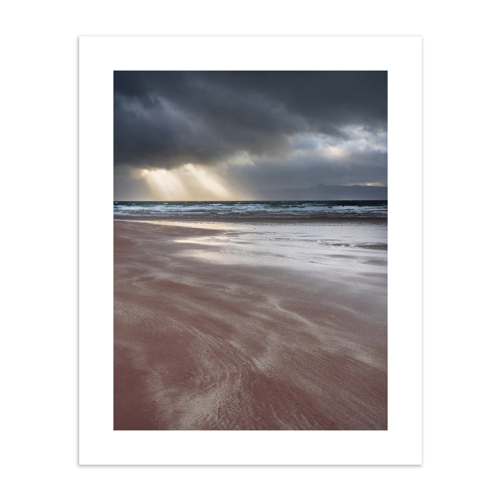Photography art print featuring a coastal view of the the beach and the sea, with beams of light peeking through moody clouds.
