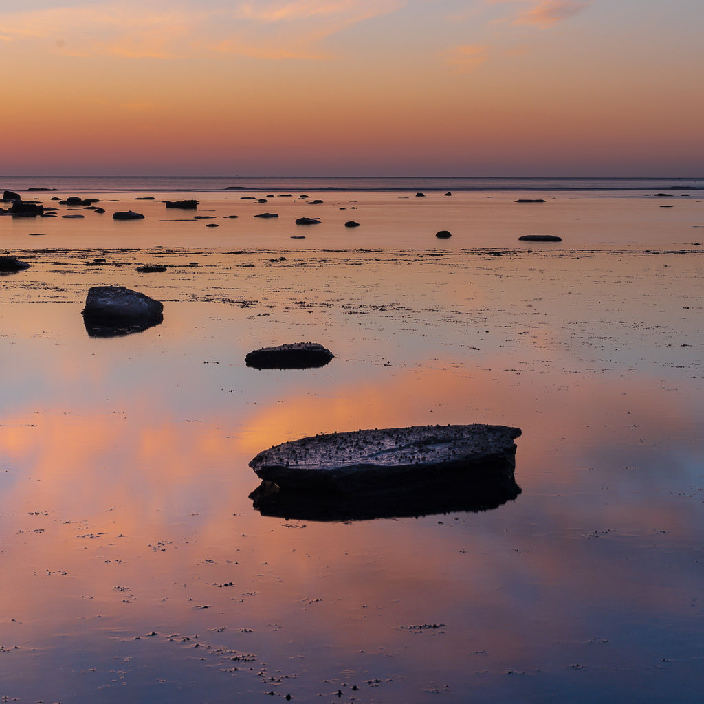 Close of up of the beach of a stunning photography art print featuring a vivid sunrise over a reflective beach.
