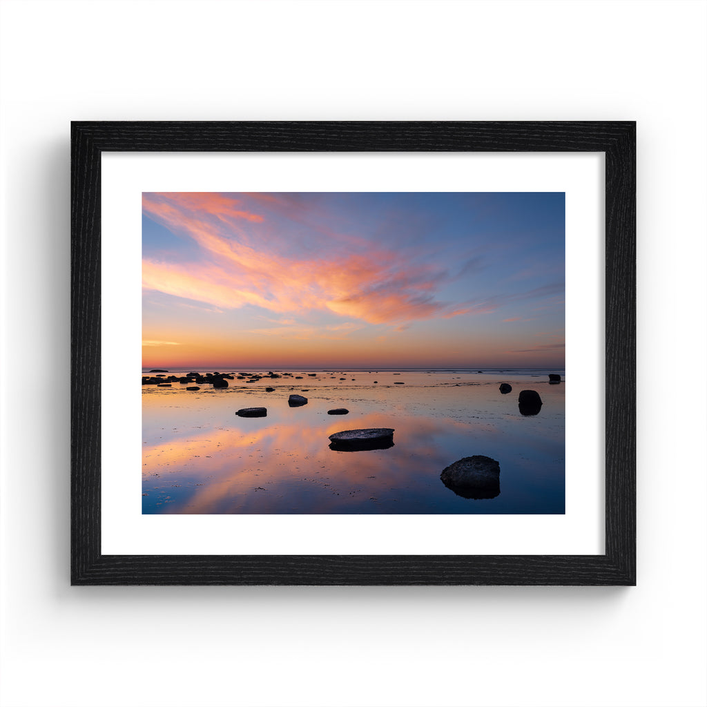 Stunning photography art print featuring a vivid sunrise over a reflective beach. Art print is in a black frame.