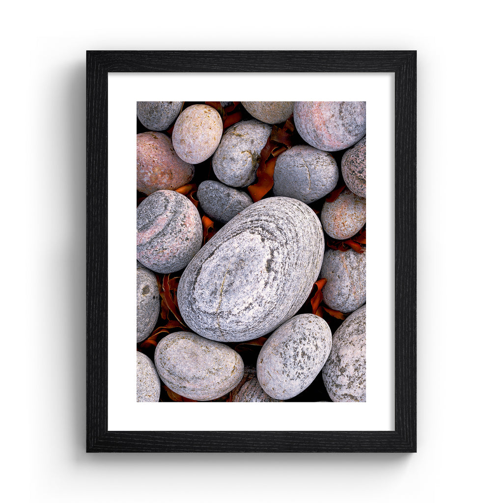 Beautifully simplistic photography art print featuring a close of up of pebbles found on a beach, in a black frame.