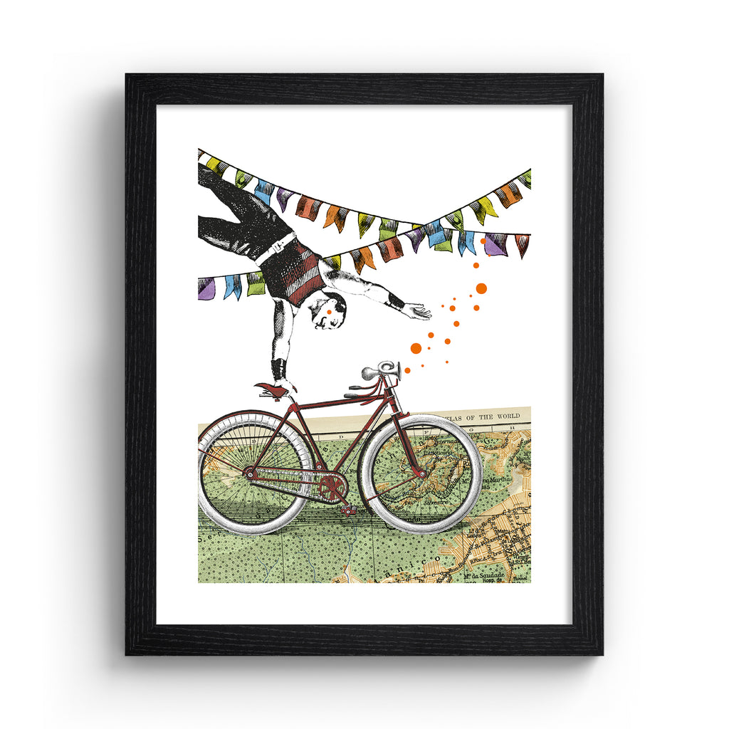 Eclectic art print featuring a man balancing off of a bicycle, perched on a map of the world. Art print is in a black frame.