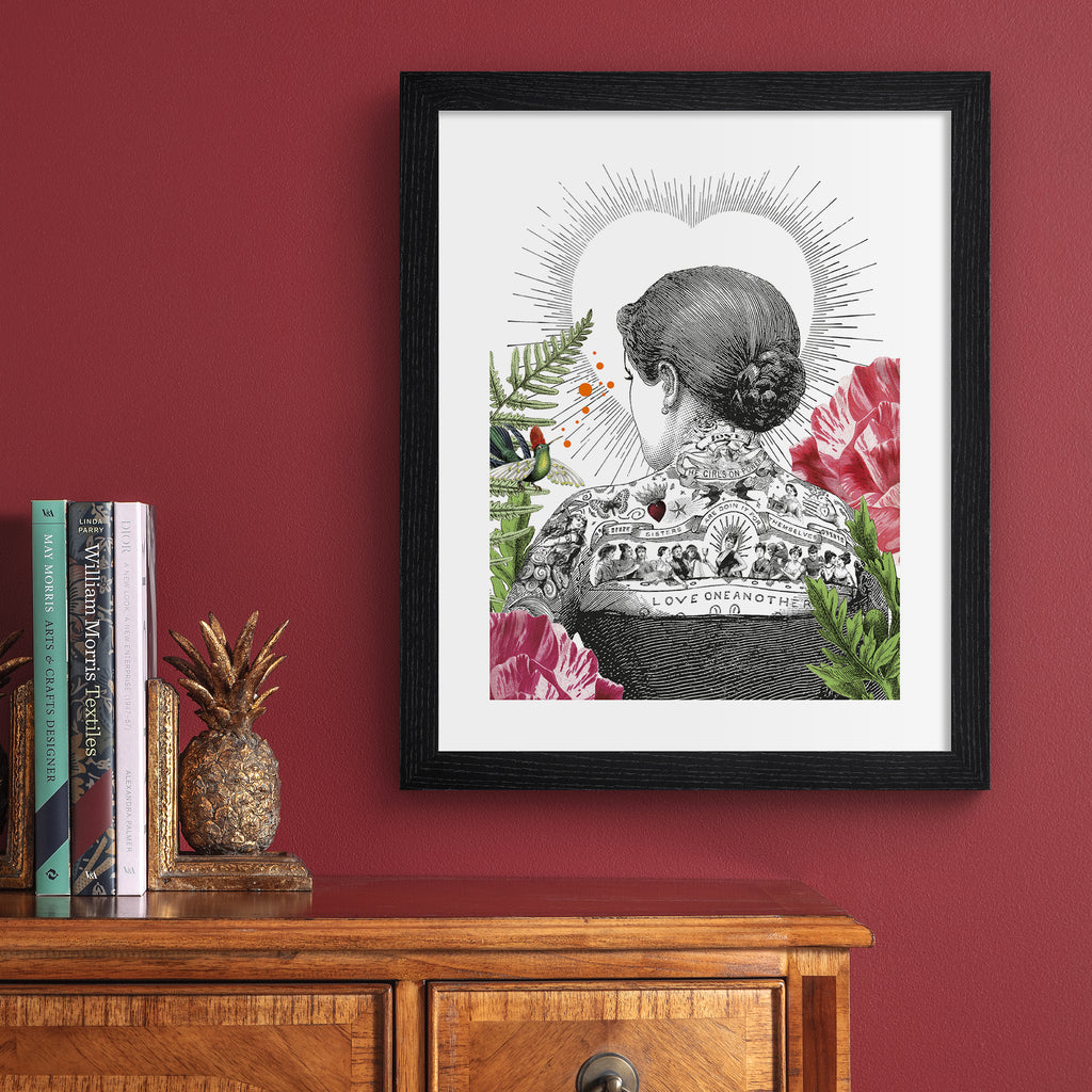 Eclectic art print featuring the back of a tattooed woman, bordered by beautiful botanicals and the outline of a love heart. Art print is hung up on a red wall.