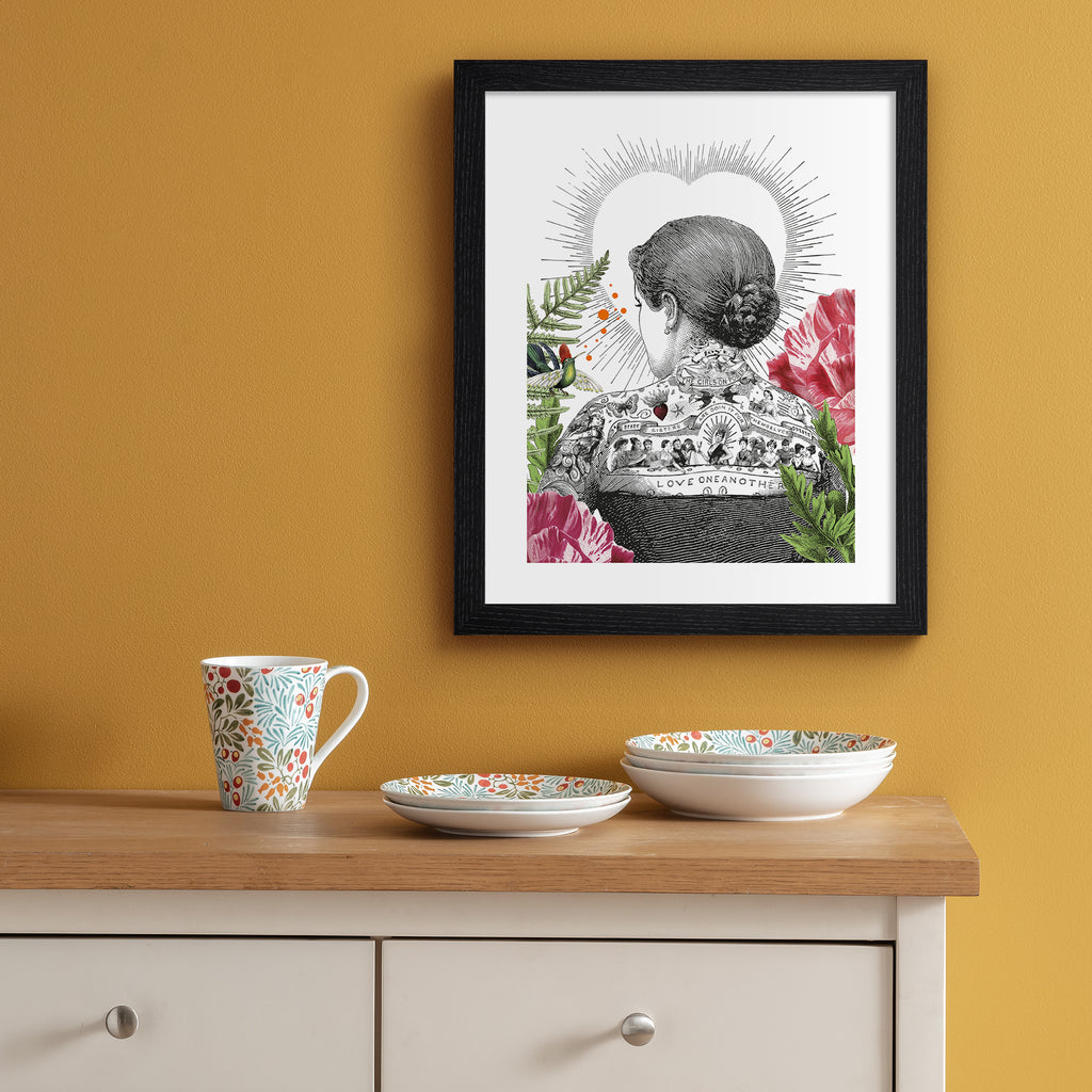 Eclectic art print featuring the back of a tattooed woman, bordered by beautiful botanicals and the outline of a love heart. Art print is hung up on an orange wall.