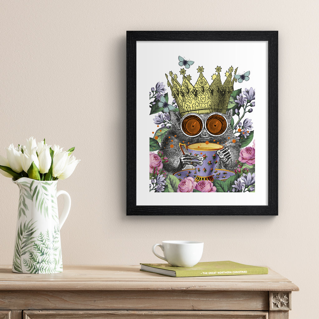 Vibrant illustration art print of a monkey surrounded by botanicals, wearing a crown and holding a cup of tea, hung up on a cream wall.