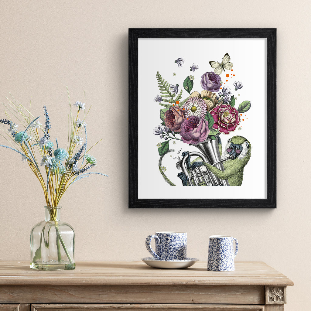 Eclectic art print featuring a monkey playing music with animals and botanicals blooming from the instrument. Art print is hung up on a beige wall.