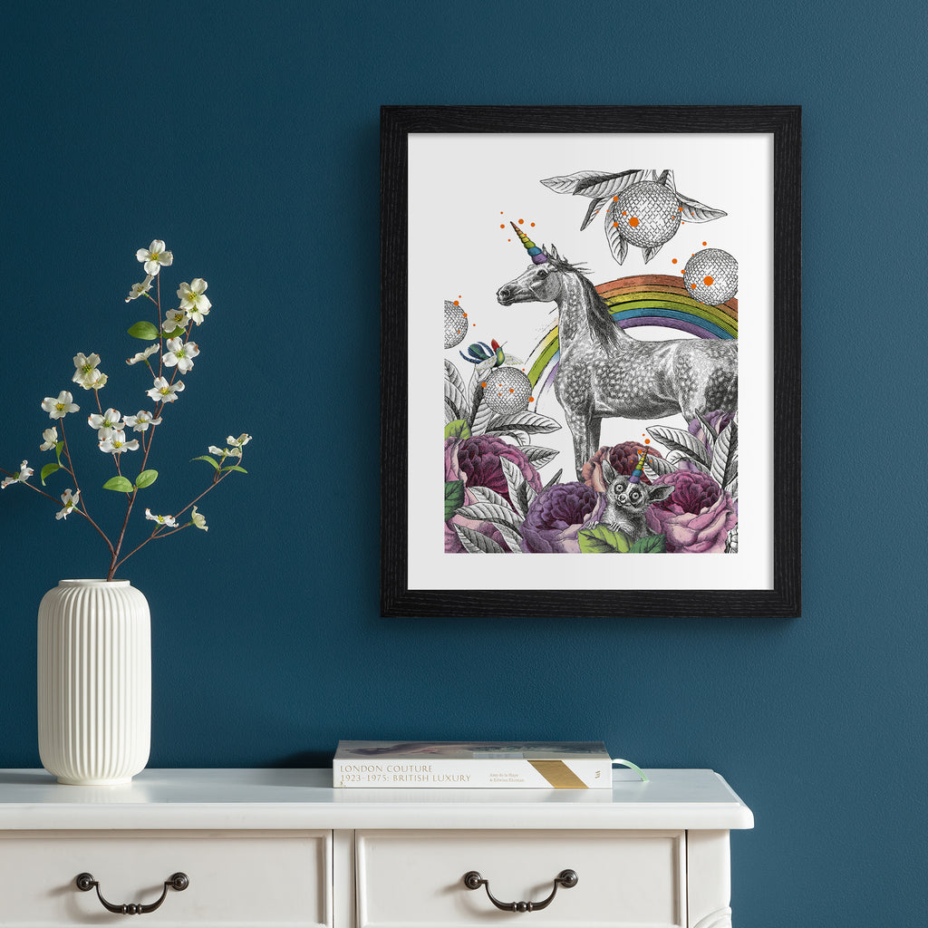 Eclectic art print featuring a unicorn standing amidst a beautiful nature scene. Art print is hung up on a dark blue wall.