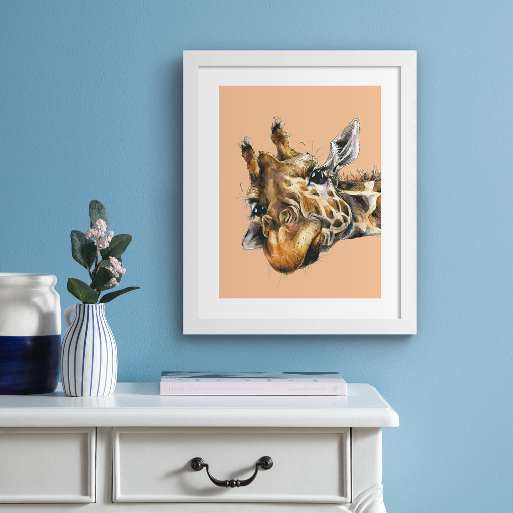 Playful art print featuring a detailed illustration of a giraffe, peeking into the frame, in front of a peach background. Art print is hung up on a bright blue wall.