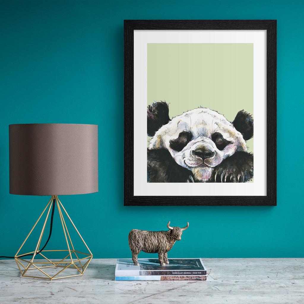 Playful animal art print featuring a happy panda popping into the frame, in front of a sage green background. Art print is hung up on a bright blue wall.