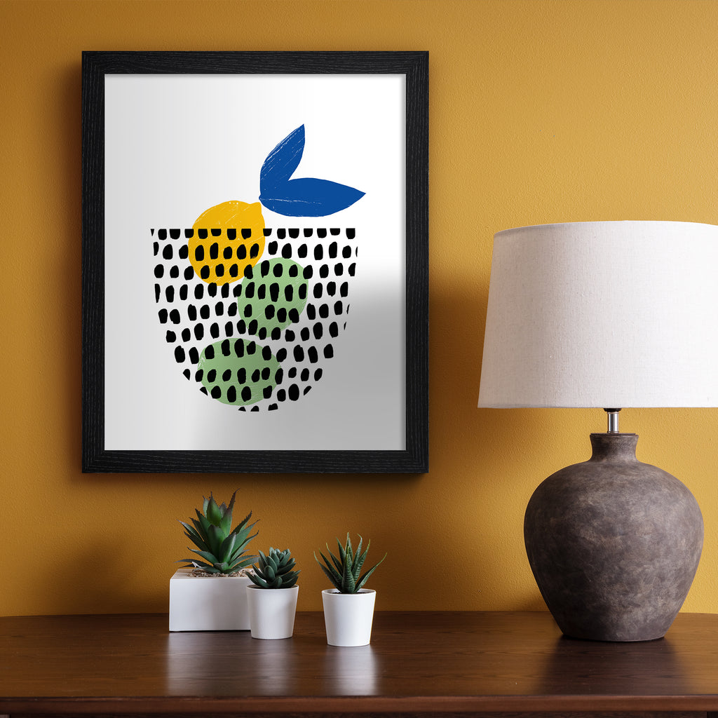 Minimalistic art print featuring a fruit basket containing lemons and limes. Art print is hung up on an orange wall.