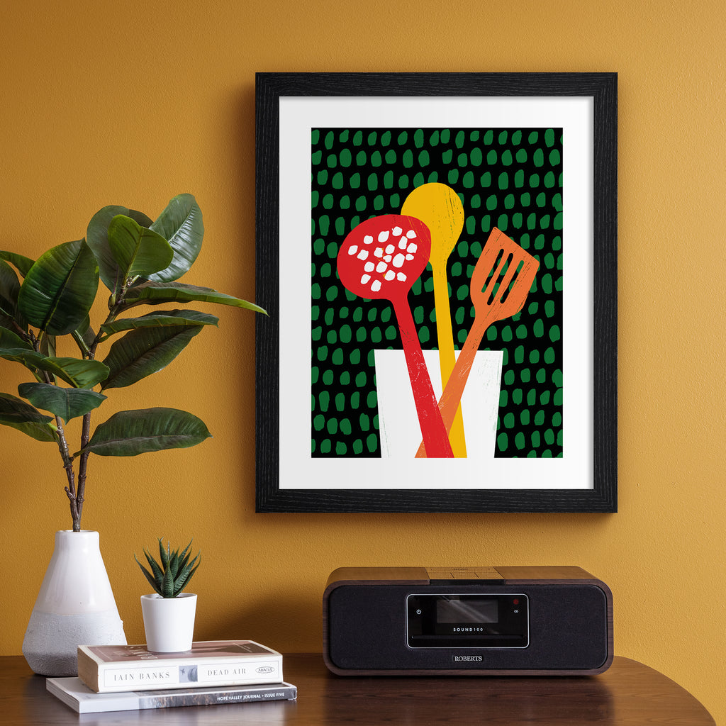 Unique art print featuring brightly coloured utensils in front of a patterned background. Art print is hung up on an orange wall.