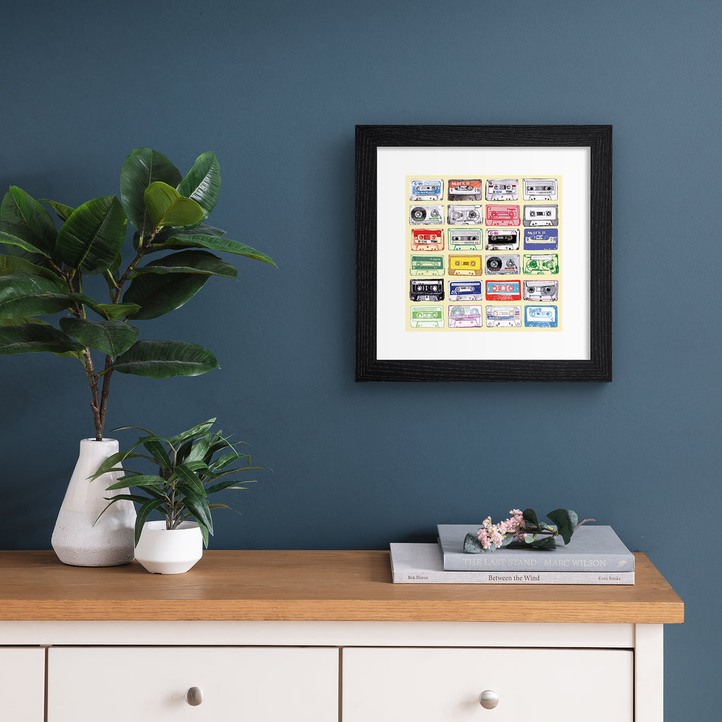 Bright art print featuring different types of mix tapes on a yellow background. Art print is hung up on a dark blue wall.