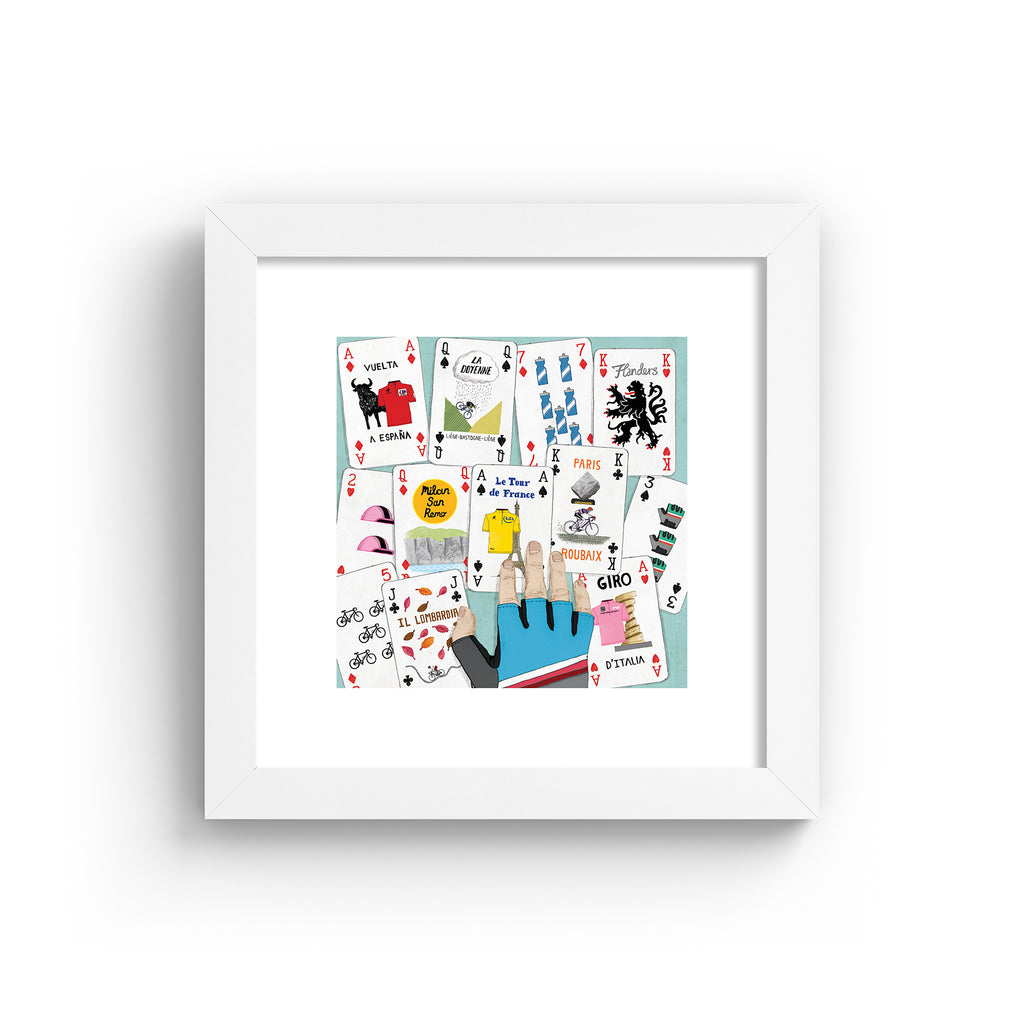 Art print featuring a deck of cards splayed out on a table. Art print is in a white frame.