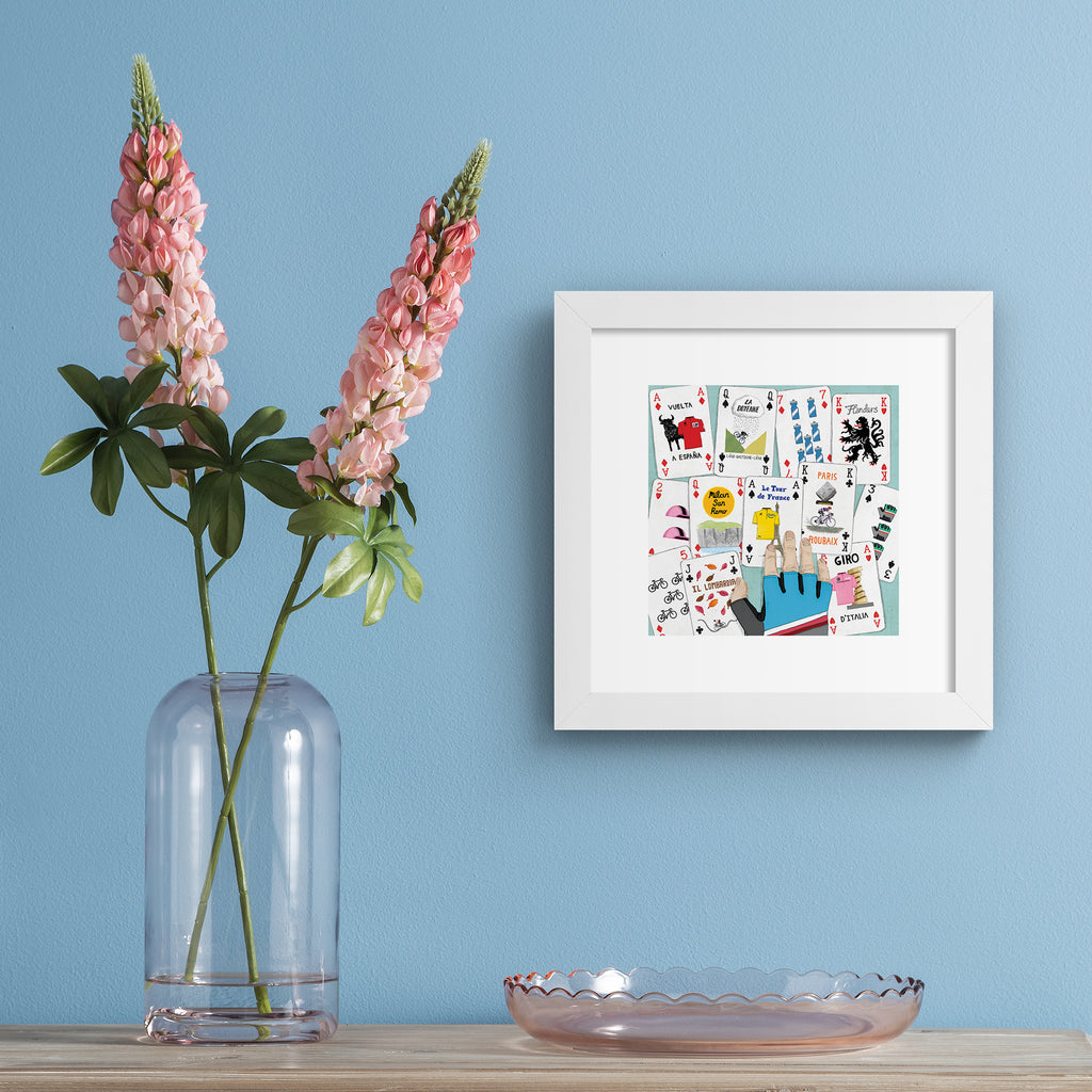 Art print featuring a deck of cards splayed out on a table. Art print is hung up on a pale blue wall.