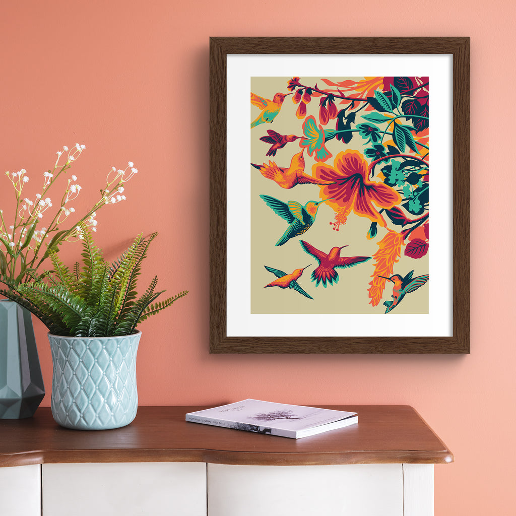 Striking art print featuring brightly coloured hummingbirds hovering above vibrant flowers.  Art print is hung up on a pink wall.
