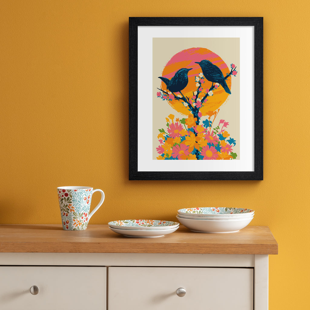 Brilliant art print featuring a detailed illustration of two birds perching on a blooming tree, in front of a bright sunset. Art print is hung up on an orange wall.