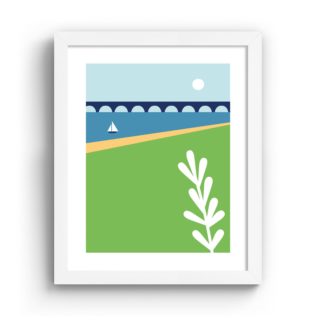 Minimalistic print containing a beautiful coastal scene, featuring a sun going down over a sailboat on still waters, near a bridge. Art print is in a white frame.