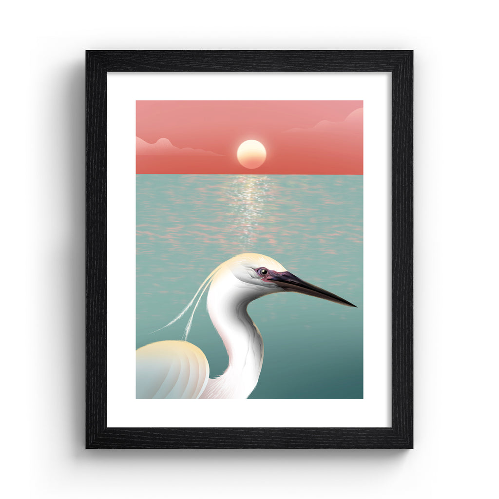 Striking art print featuring a white egret posing in from of the ocean, as the sun sets on the horizon. Art print is in a black frame.