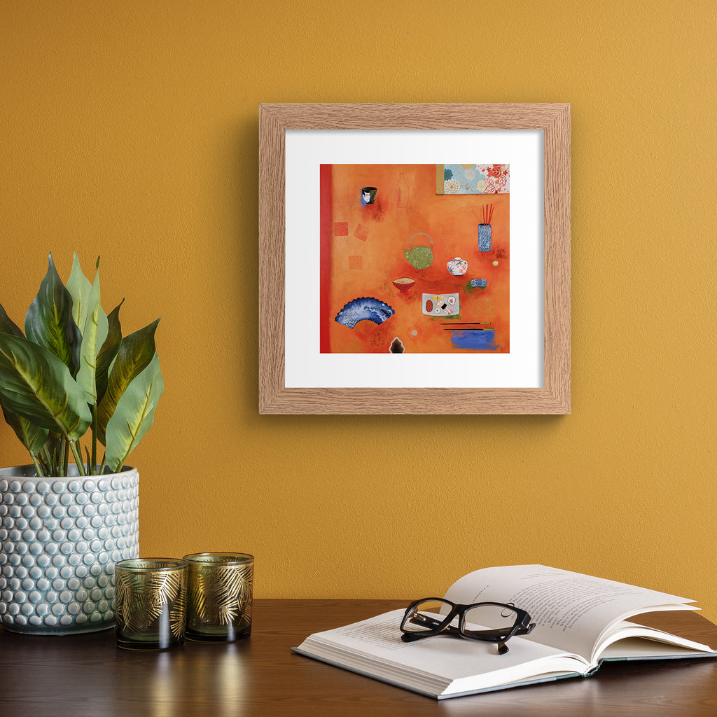 Bright art print featuring different household objects placed on a bright orange background. Art print is hung up on an orange wall.