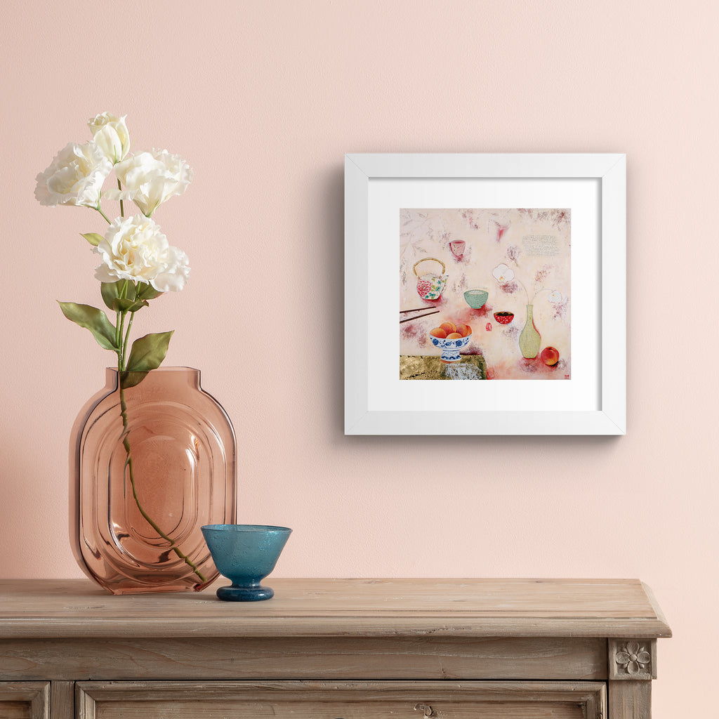 Cosy abstract print containing a food spread of peaches and tea, laid out on a pink background. Art print is hung up on a pale pink wall.