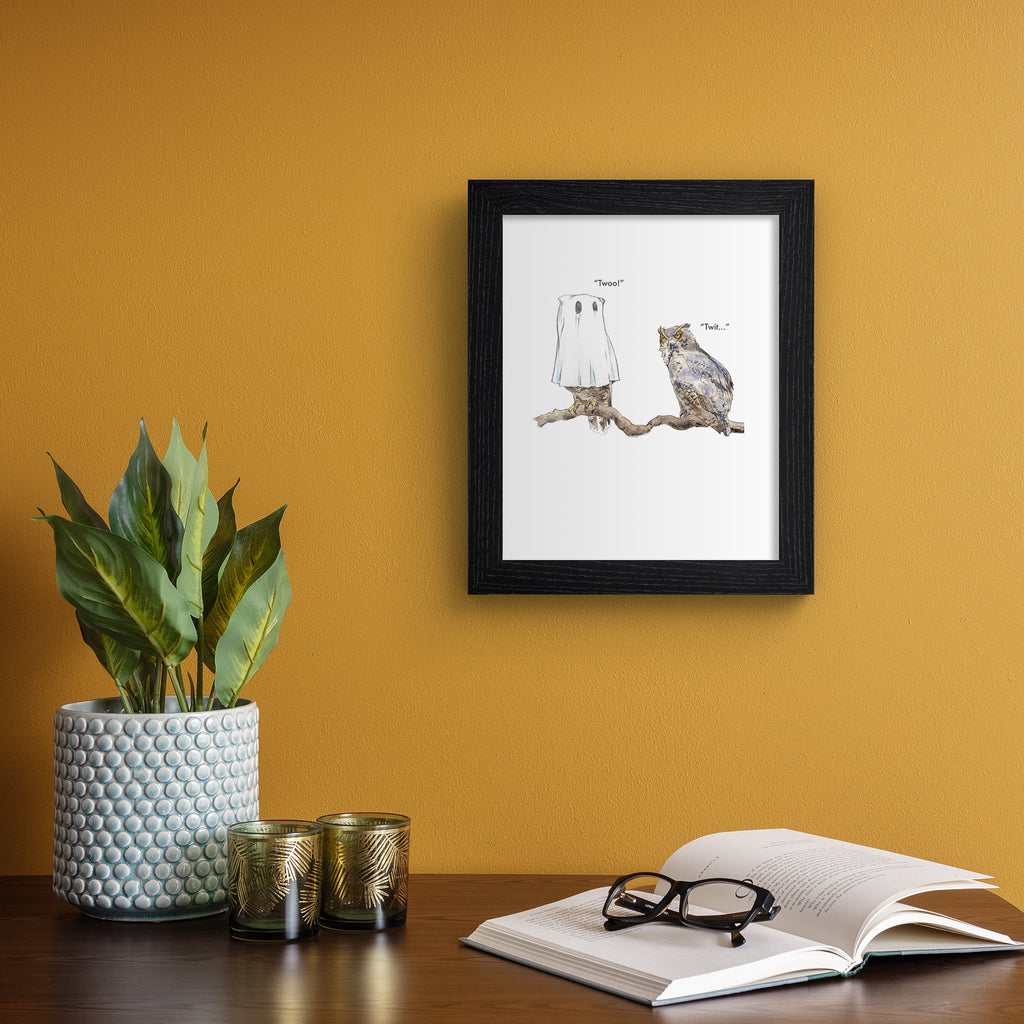 Humorous art print featuring an illustration of two owls perched together. One owl wears a ghost costume and says 'Twoo!'  Art print is hung up on an orange wall.
